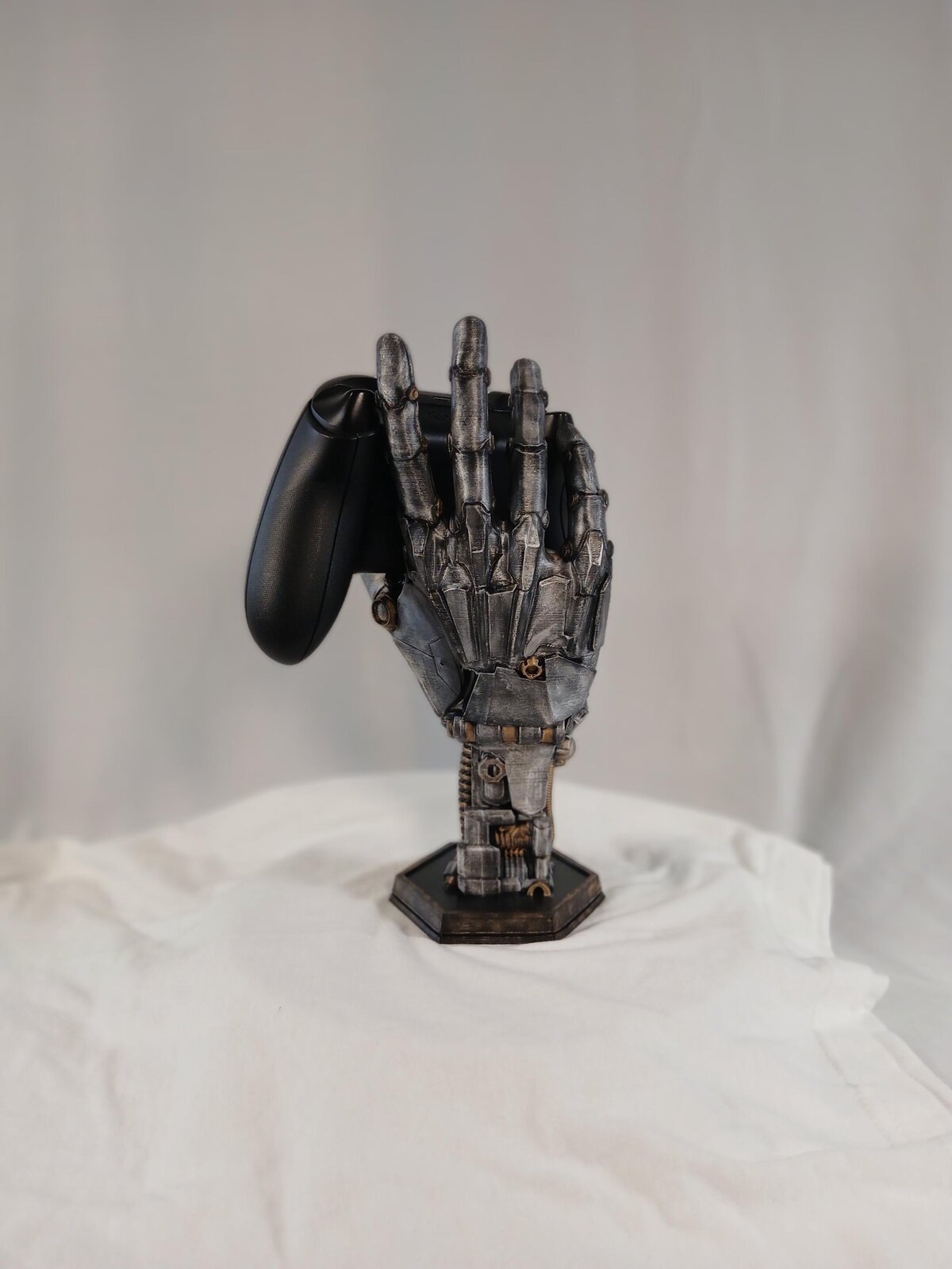 3D printed robotic hand shown holding a game controller, side view
